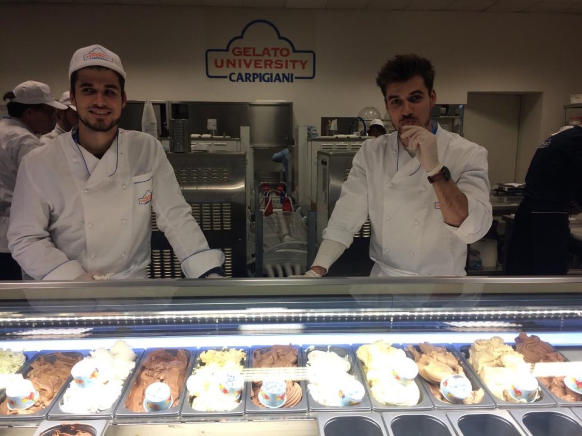 Les deux frères en tenue de glacier à la Carpigiani Gelato University de Bologne, derrière une vitrine de gelati